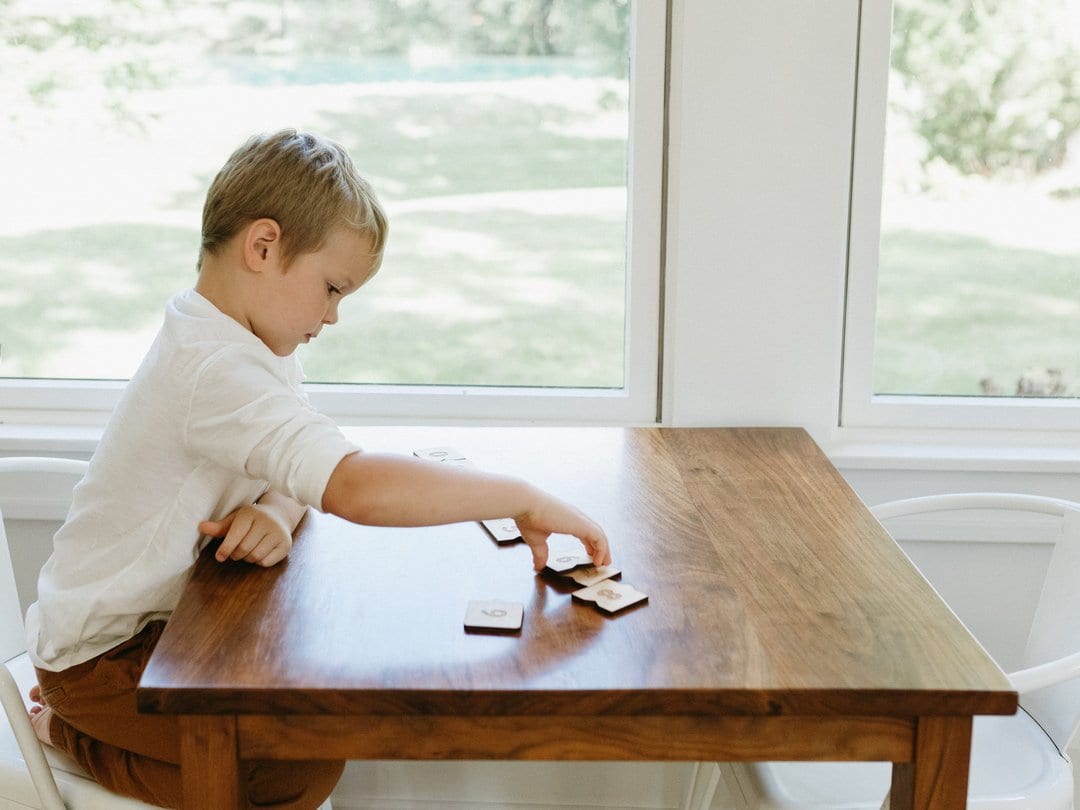 child playing with wooden number puzzle on a wooden table
