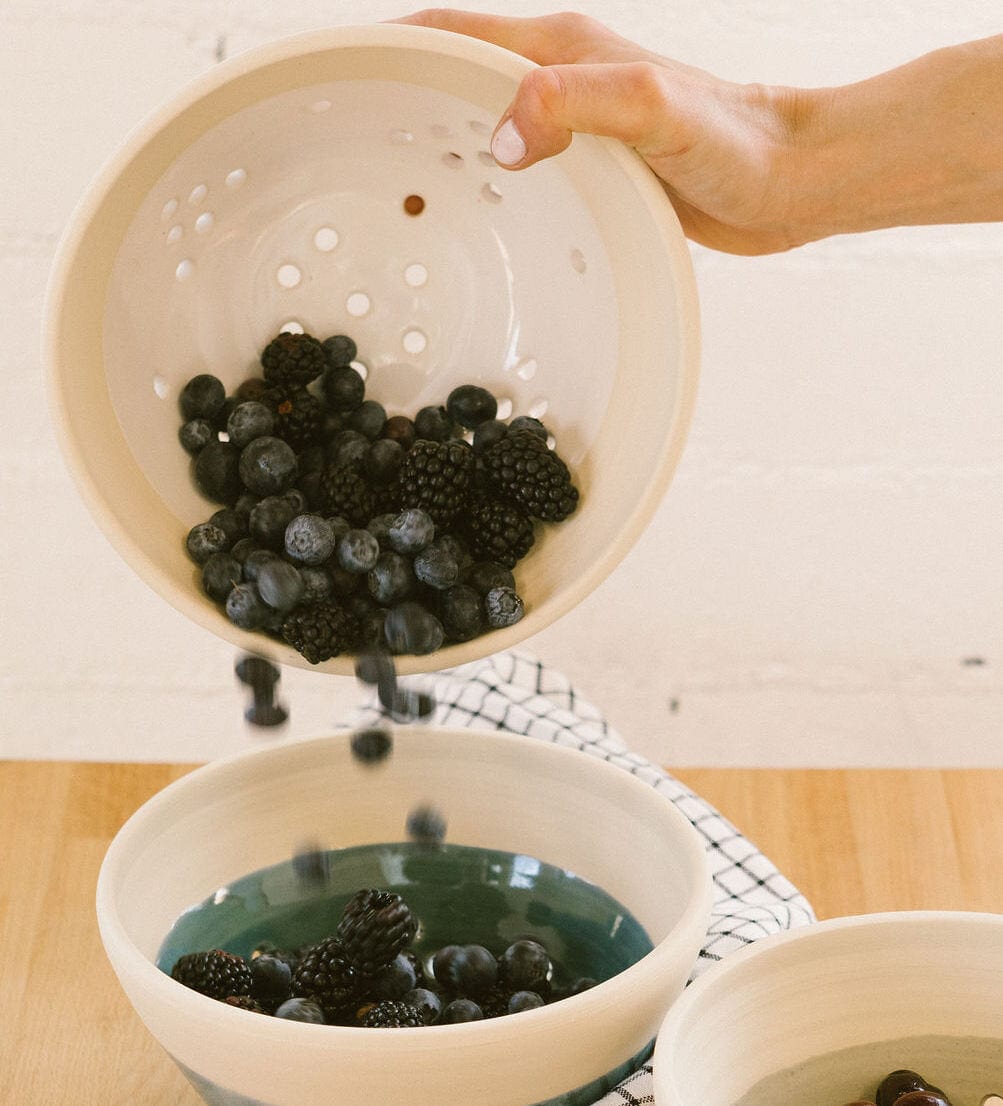 pouring berries out of a berry bowl into another berry bowl of a different color