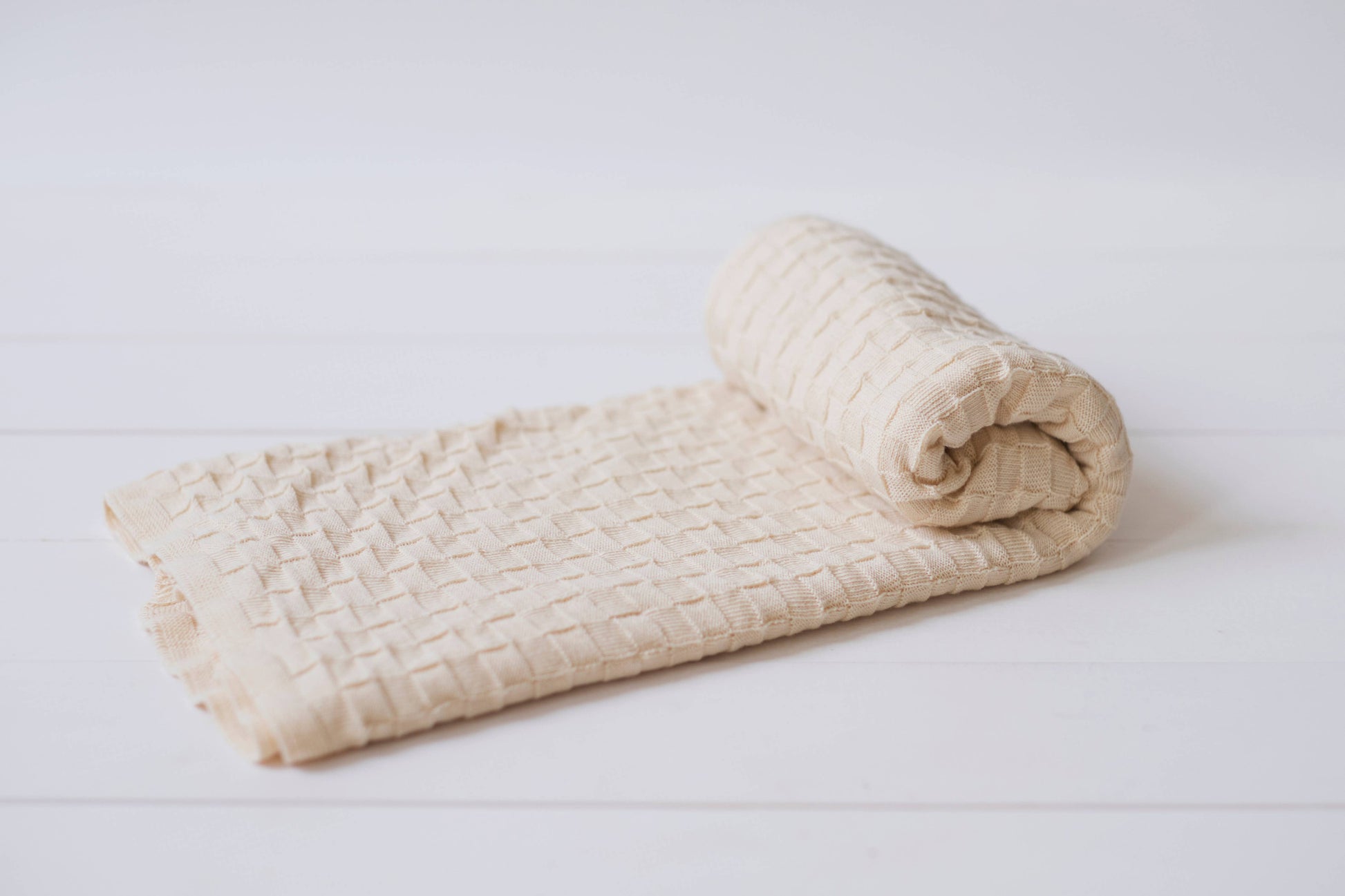 Organic Cotton Basketweave baby blanket unrolling to show pattern and Natural color