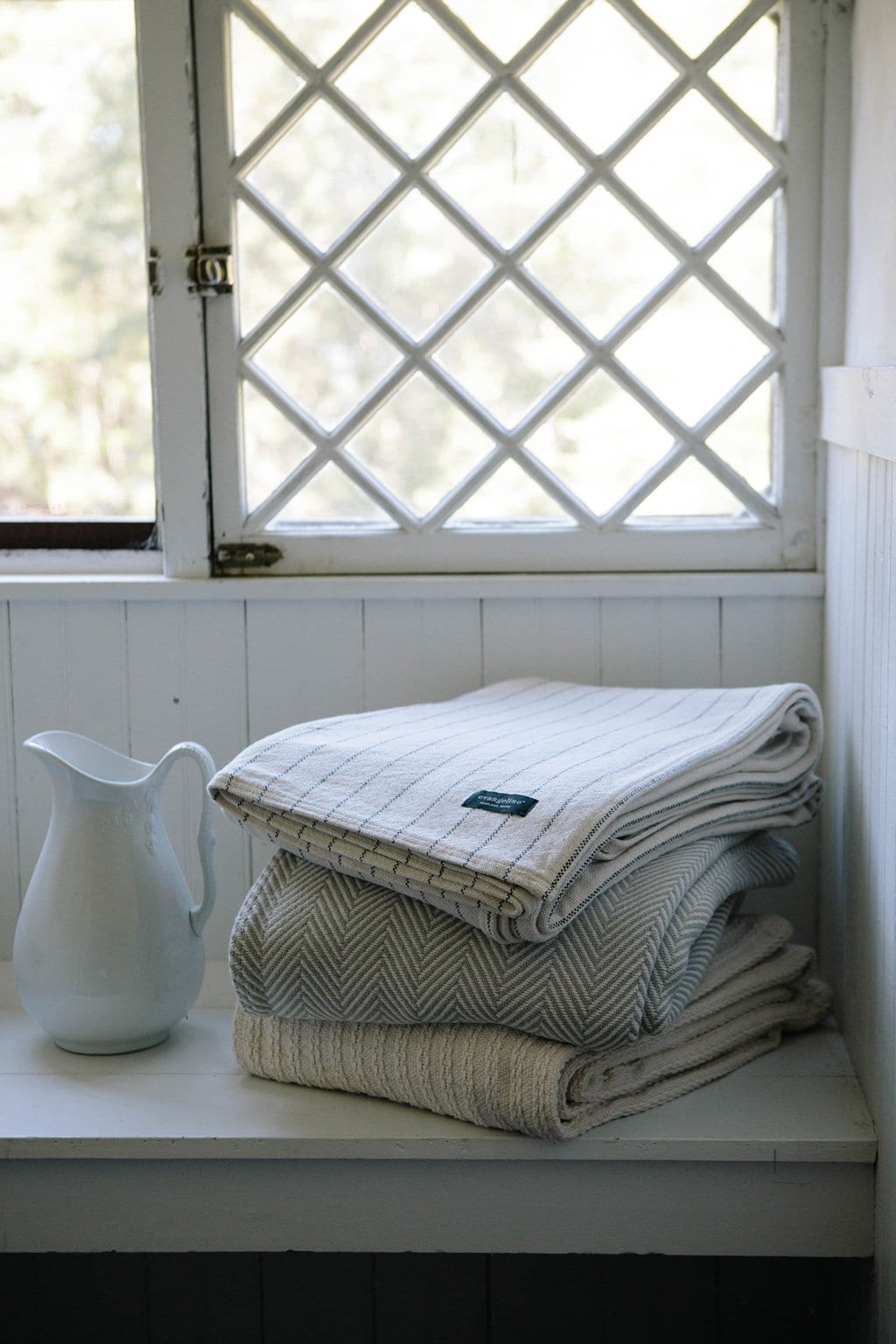 Pinstripe throw blanket on top of a stack of blankets