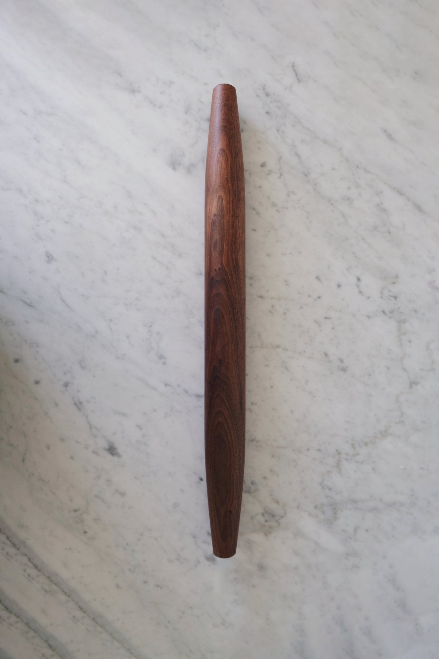 Walnut rolling pin on a marble countertop