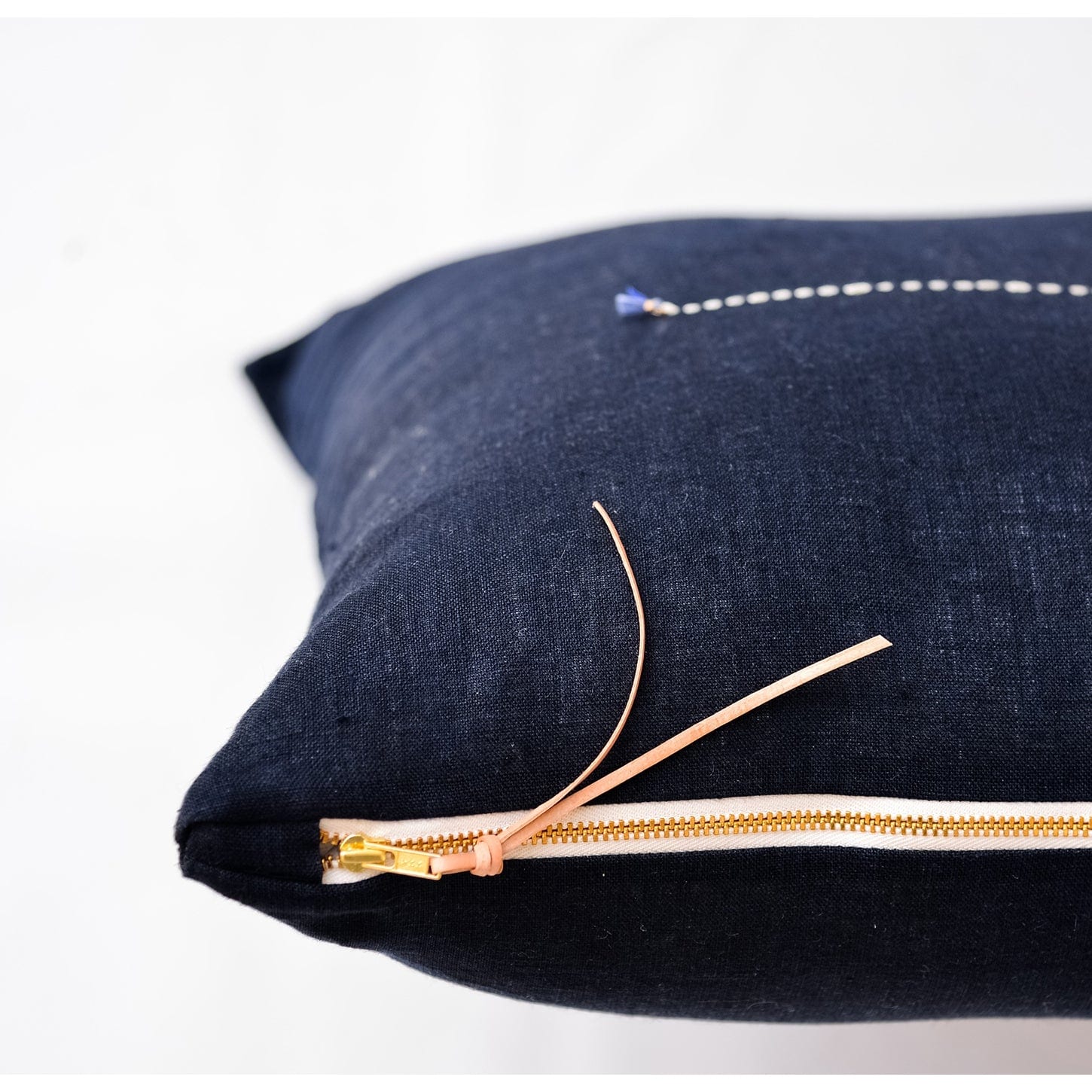 Navy Linen Pillow with close up of brass zipper and leather tassle