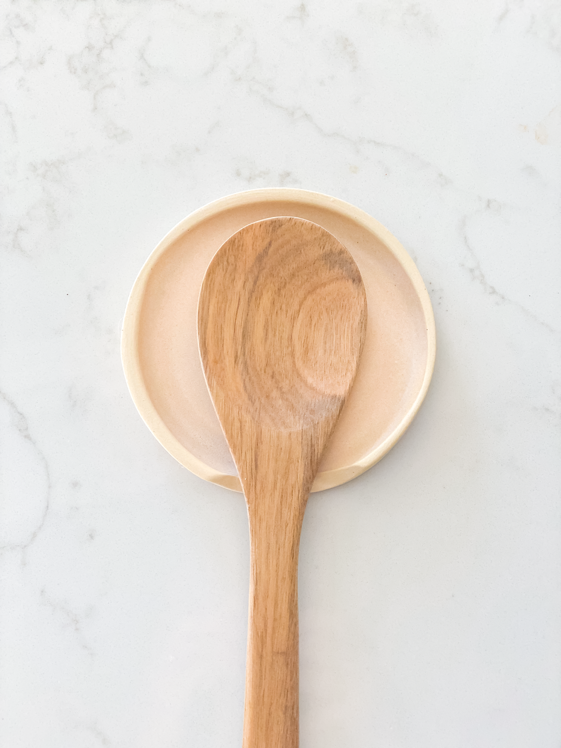 Coral spoon rest with wooden spoon on top of it
