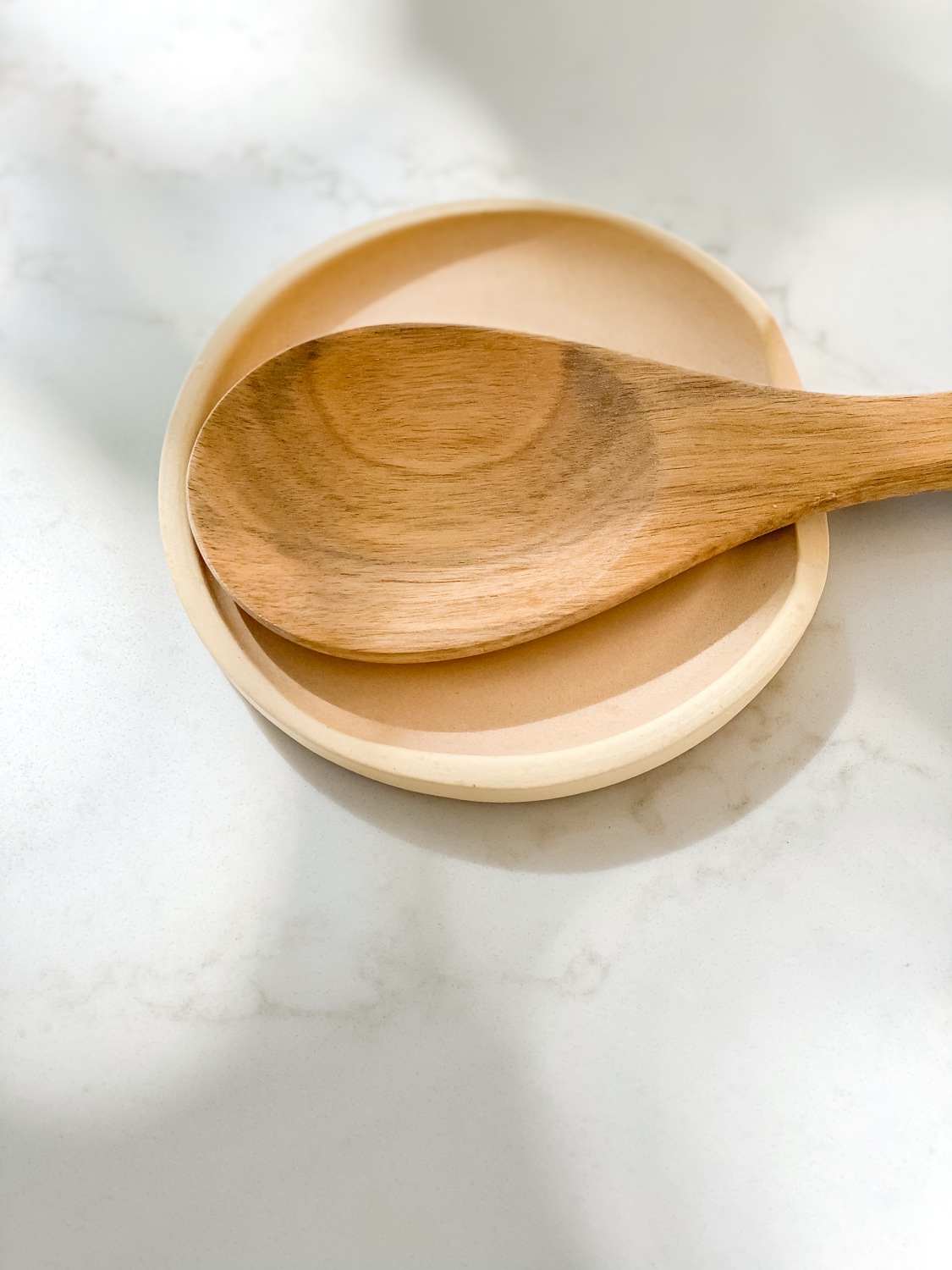 coral spoon rest with wooden spoon on marble counter