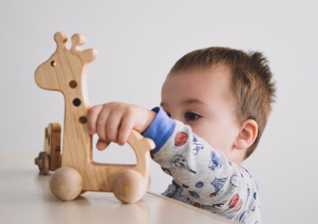boy playing with wooden giraffe push toy 