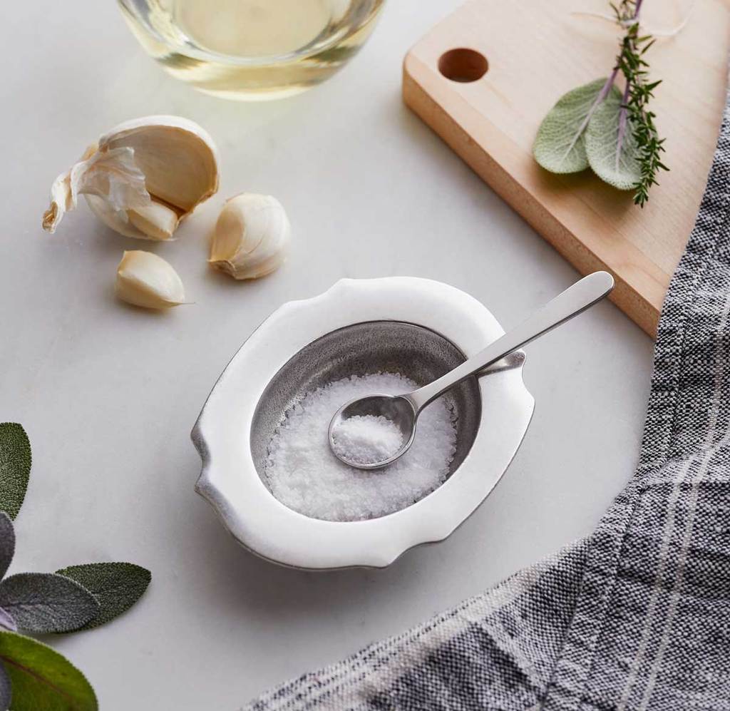 Salt Cellar (filled with salt) and Spoon on a dining table or countertop.  