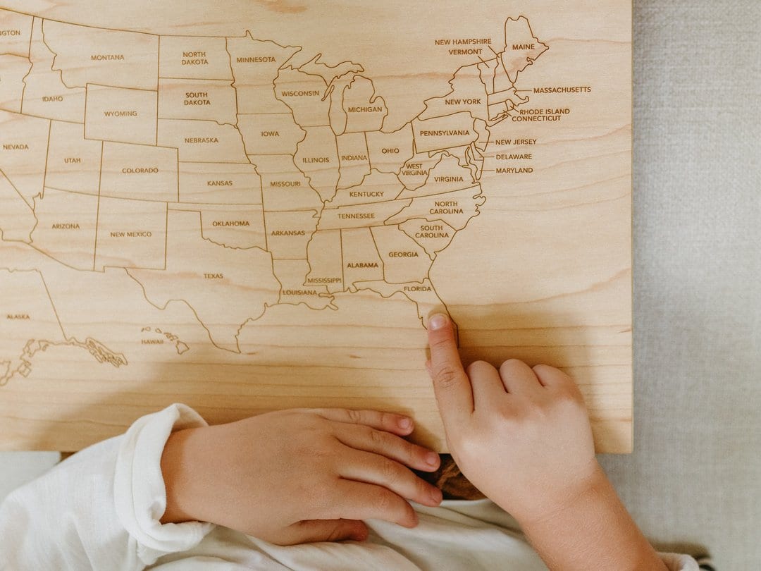 child pointing at Florida on an engraved wooden learning map of the united states