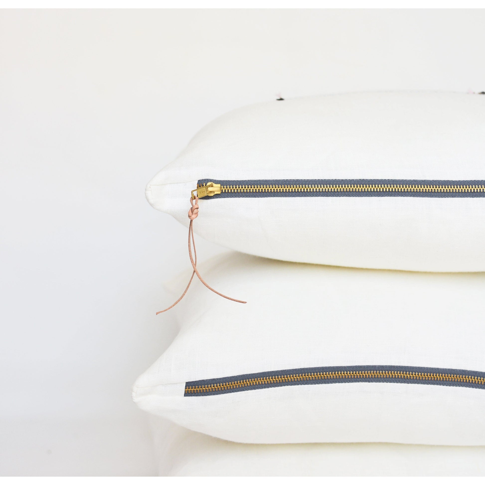 White lumbar linen pillow with brass zipper and leather tassel