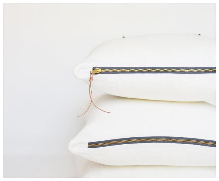 Stack of 2 white linen pillows with brass zippers and leather tassels exposed
