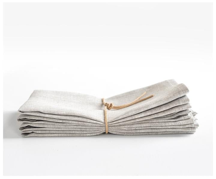 Stack of oatmeal linen napkins with leather string wrapped around them.