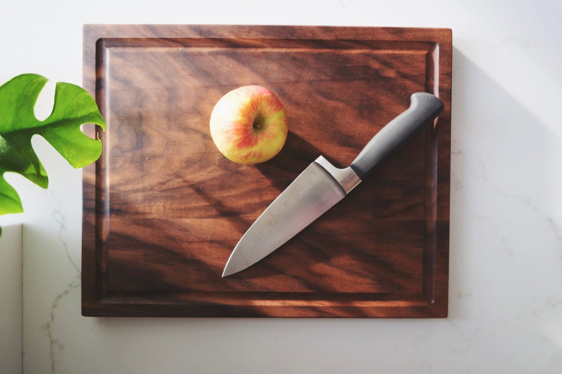 small walnut cutting board with an apple and knife on top