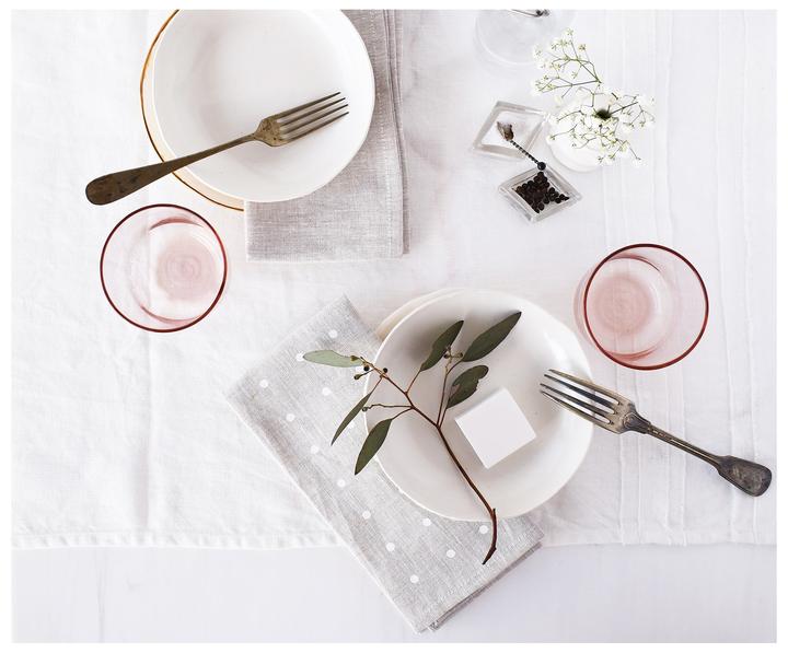 linen runner with oatmeal and white dot Linen Napkins folded atop a table with small plates and glassware