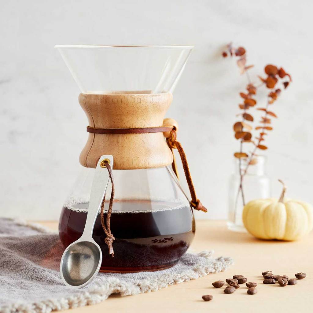 Pewtery coffee scoop leaning against a pour over glass