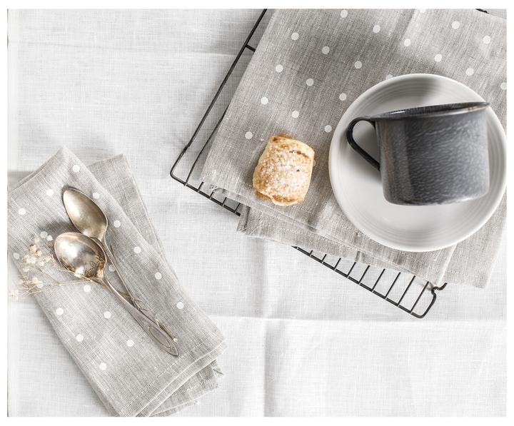 100% linen oatmeal and white napkins on a dining table with silverware, biscuit, and coffee mug. 